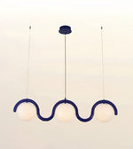 A modern three-light linear pendant chandelier with a wavy, S-shaped dark blue frame and three frosted white globe shades, suspended from a matching dark blue ceiling canopy.