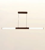 A modern linear pendant light fixture with a horizontal white ribbed glass tube and dark brown metal accents, suspended against a plain light beige background.