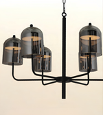 A modern multi-light chandelier with a matte black metal frame and six smoke-tinted glass bell shades, shown against a plain off-white background.