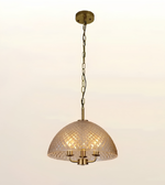 A dome-shaped pendant light with a textured, diamond-patterned glass shade and a brass-finished metal frame, hanging from a matching brass ceiling canopy and chain against a plain off-white background.