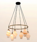 Modern circular ring chandelier on white background featuring multiple marble-effect glass pendant lights with brushed brass accents and warm ambient illumination.