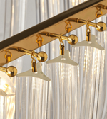 Gold ceiling light fixture with white lampshades against a curtain background