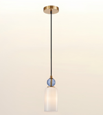 A modern pendant light fixture with a round gold ceiling canopy, a black cord, a small blue ribbed glass accent sphere, and a frosted white glass cylindrical shade, shown against a light beige gradient background.