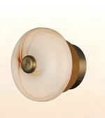 Modern circular marble-effect glass wall light with brushed brass accents, providing warm ambient illumination for contemporary interiors.