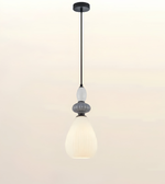 A modern pendant light with a black metal canopy and cord, featuring a textured gray decorative collar and a large, ribbed white glass shade that glows with warm light, set against a plain off-white background.