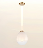 A modern pendant light with a matte white teardrop-shaped glass shade, a black cord, and brushed gold metal hardware, shown against a soft off-white background.