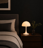 Modern mushroom table lamp with soft warm glow placed on bedside table in luxury bedroom