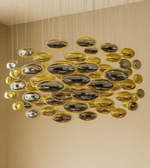 Modern chandelier with gold and silver oval designs on a beige wall.
