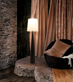 Minimalist black floor lamp styled next to sofa and curtains at night