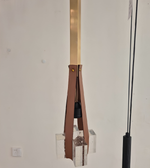 Modern pendant light with brown and gold accents on a white wall.