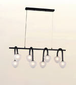 Modern linear chandelier with six frosted glass globe shades suspended from a black metal frame, shown against a plain light beige background.