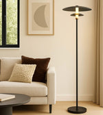 Modern floor lamp next to a beige sofa with cushions in a living room setting.