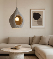 Grey sculptural foam pendant light with stone-like texture above a modern table.