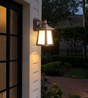 Metal outdoor wall lantern installed near a porch door with soft warm lighting.