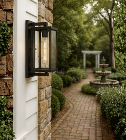 Black framed exterior wall light with clear glass and filament bulb.