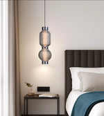 Modern glass pendant light over bedside table in elegant bedroom setting