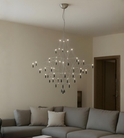 Modern chandelier hanging above a gray sectional sofa in a living room.
