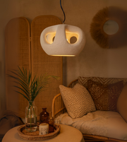 Handcrafted organic foam pendant light in grey, softly glowing in modern cozy interior.