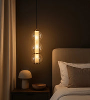Modern glass pendant light above nightstand in cozy bedroom with neutral decor