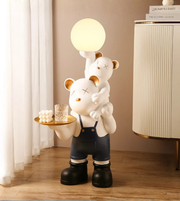 Playful bear duo floor lamp sculpture holding a glowing globe light in a modern interior setting