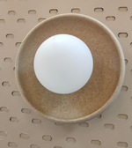 Gold disc wall light with frosted glass globe mounted on neutral wall