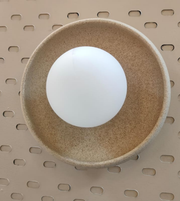 Gold disc wall light with frosted glass globe mounted on neutral wall