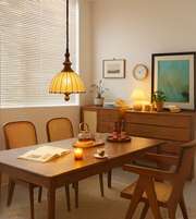 Solid wood and fabric pendant light with copper body finish, hanging above a wooden dining setup, casting a warm ambient glow.