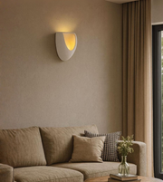 Moon Arc sculptural grey wall light glowing softly above beige sofa.