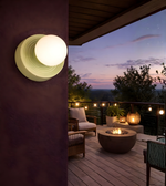 Green indoor wall light with glowing frosted globe in cozy interior setting