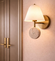 Modern bronze wall sconce with fabric shade and stone accent mounted beside bedroom door