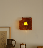 Amber textured glass square wall light with warm illuminated center enhancing indoor décor