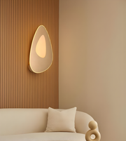 Modern organic-shaped wall sconce with warm diffused LED lighting in a minimal living room