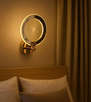 Golden infinity halo wall light with spiral LED effect mounted above bed