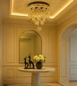 Oro Fleur gold flush chandelier with floral crystal details above marble foyer table.