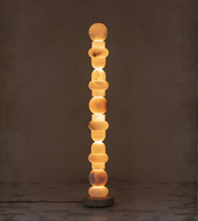 Vertical marble floor lamp with stacked stone design against dark background
