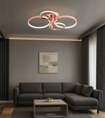 Lumicircle modern ceiling light with rose gold rings above sofa.