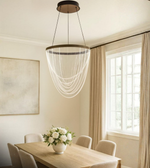 Acrylic drape chandelier hanging over a modern dining table in beige room interior