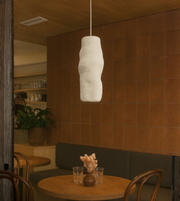 Handcrafted ceramic style wavy pendant light in warm-toned dining, cafe interior