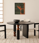 Modern round dining table with sculptural legs, black bowl centerpiece, and minimalist chairs