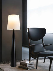 Modern black floor lamp placed beside armchair in contemporary living room