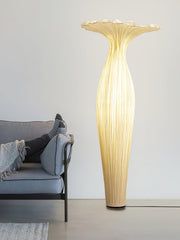 Tall sculptural floor lamp with soft golden glow beside modern sofa