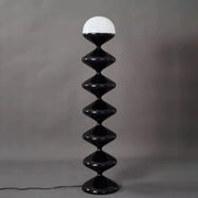 Close-up of glossy black geometric floor lamp with dome diffuser