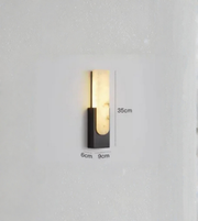 Vertical marble wall sconce with black metal base and warm glow