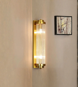 Gold wall sconce with glass panels on a beige wall.