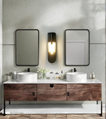 Bathroom vanity with two sinks, mirrors, and decorative items against a tiled wall.