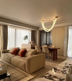 Modern living room with beige sofa, dining table, and chandelier.
