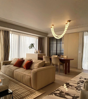 Modern living room with beige sofa, dining table, and chandelier.