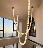 String of lights hanging from the ceiling in a room with large windows.