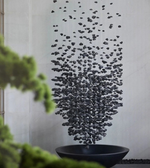Decorative wall art with black pebbles on a light gray wall