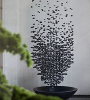 Decorative wall art with black pebbles on a light gray wall